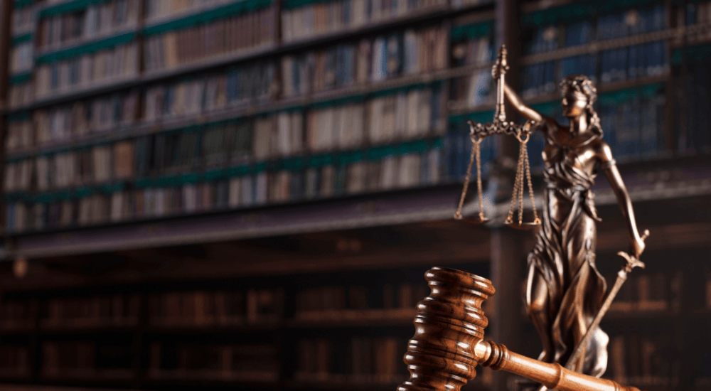 Escultura de la justicia frente a libros de derecho penal en Chile